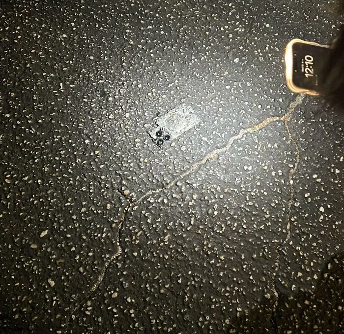 Teléfono móvil caído en el suelo con fondo de asfalto rugoso, ejemplo de fotos de vacaciones que no salieron bien.