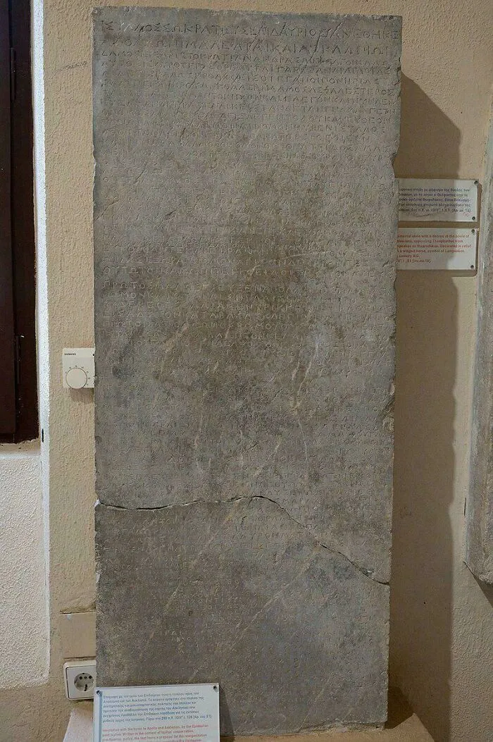 Ancient stone inscription still remains undiscovered to this day, featuring faint Greek text on a museum wall.