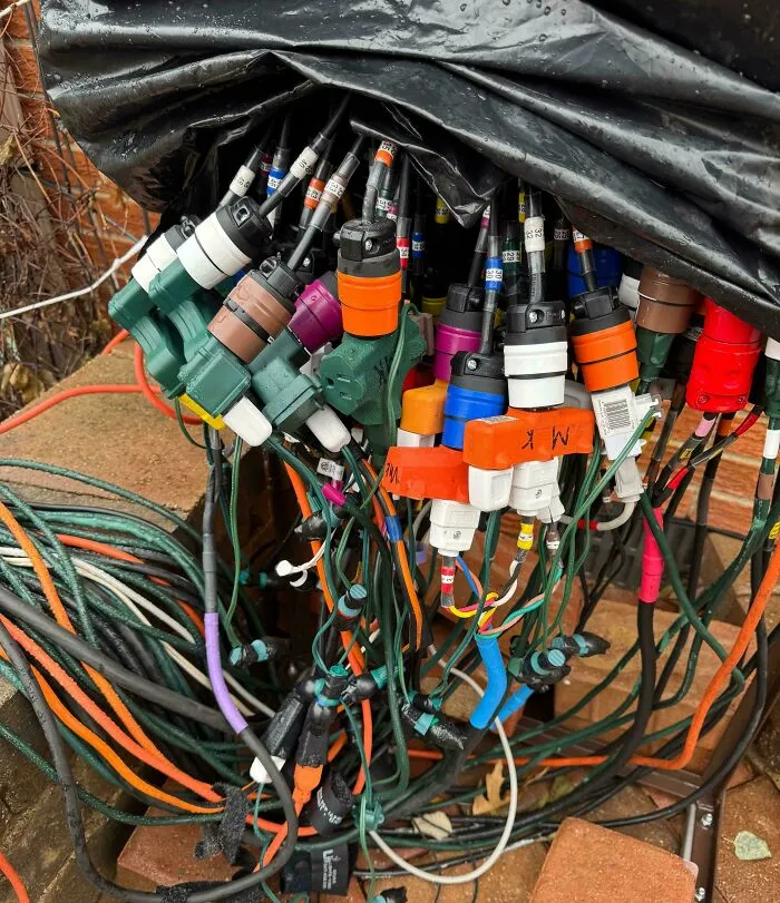 Tangled and overloaded electronics wiring showing improper handling and risky soldering connections outdoors.