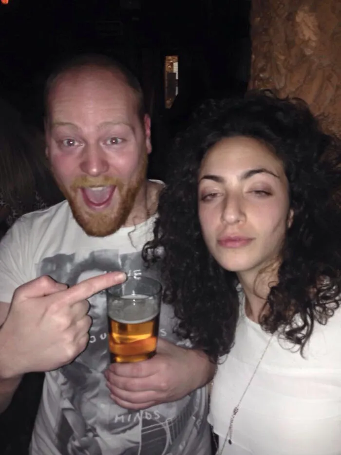 Man holding beer excitedly points at woman with curly hair, a humorous moment from celebrity lookalike fails shared online.