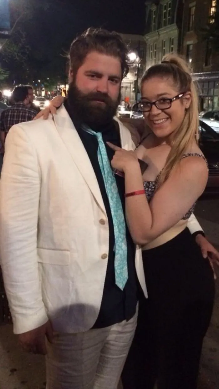 Man in white suit and woman smiling and posing together at night, a funny celebrity lookalike moment shared online.