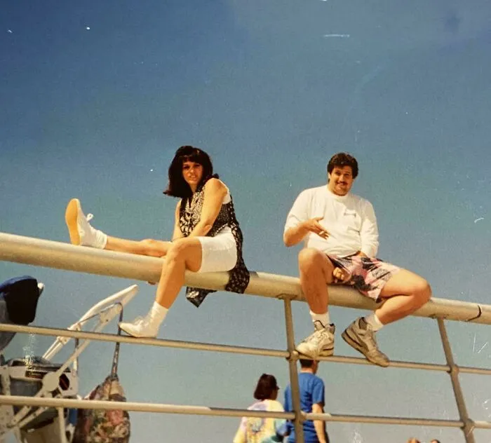 Dos personas jóvenes posan relajadas sobre barandales con estilo casual y zapatos visibles, disfrutando un momento divertido.