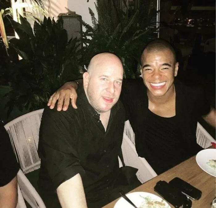 Two men posing for a casual photo at a dinner table, featured in Johnny Derp celebrity fail images online.