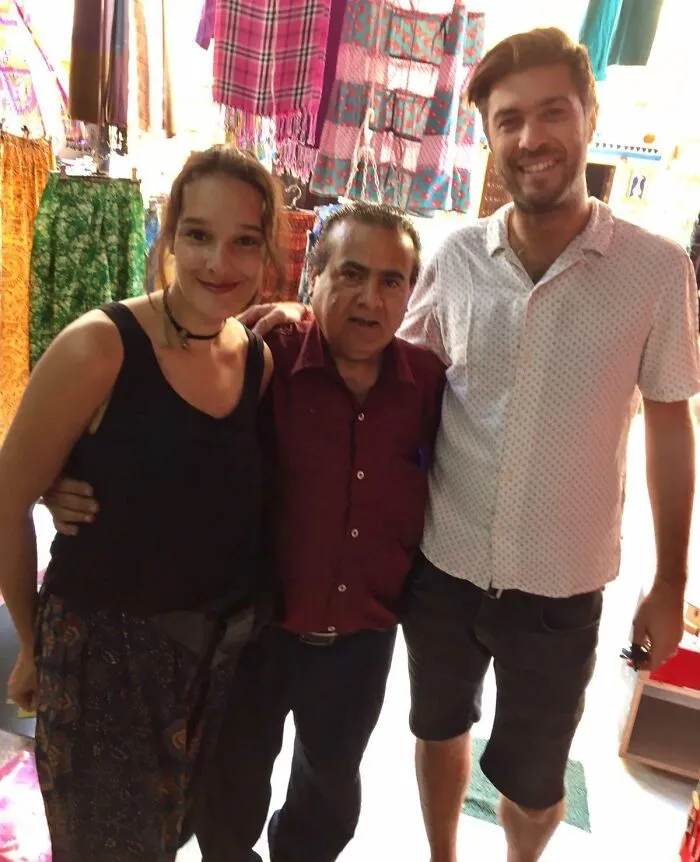 Three people posing in a colorful market setting, a photo shared as a funny celebrity lookalike moment online.
