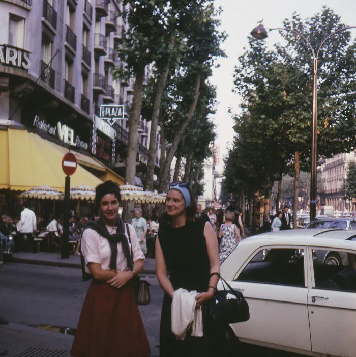 Dos mujeres sonrientes en la calle, disfrutando un momento divertido durante una época muy diferente.