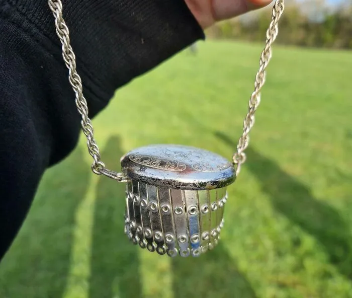 Expandable Metal Circle With Chain And Lid. This Top Comes Off But Is Attached With A Hinge. When The Top Is Off It Can Expand