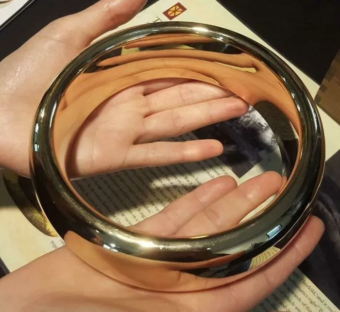 Manos sosteniendo un espejo reflectante circular que muestra la explicación del tamaño humano real.
