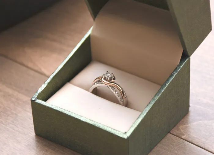 Anillo de compromiso en caja verde, ilustrando momentos donde teléfonos revelaron verdades ocultas.
