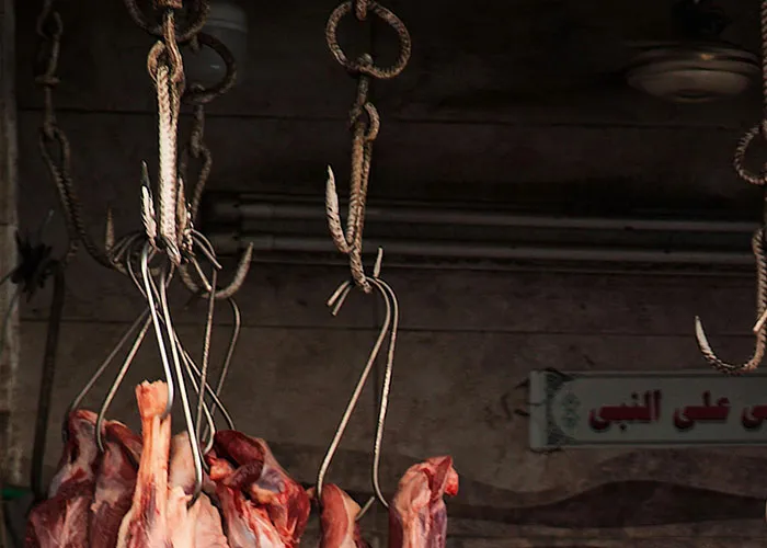 Raw meat hanging from hooks in a dimly lit room, evoking chilling and terrifying true stories atmosphere.