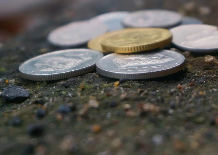 Close-up of various coins scattered on a rough surface, illustrating small monetary value in criminal fails context.