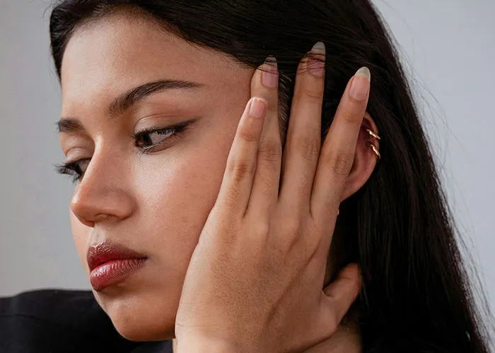 Close-up of a woman looking away with a hand on her face, conveying discomfort related to creepy behavior experiences.