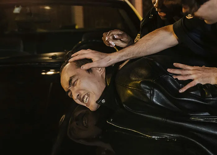 Man in a leather jacket being arrested by police officers in a nighttime scene of criminal fails.