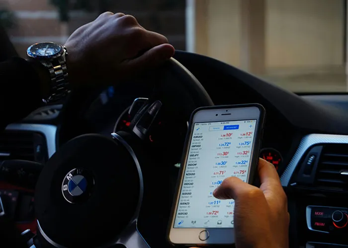 Person holding phone while steering BMW car, illustrating distracted behavior linked to criminal fails moments.