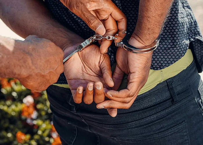 Hands in handcuffs being secured by an officer, illustrating one of the criminal fails caught on camera outdoors.