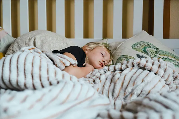 Young child sleeping peacefully under a soft blanket, evoking themes of bizarre and paranormal experiences.