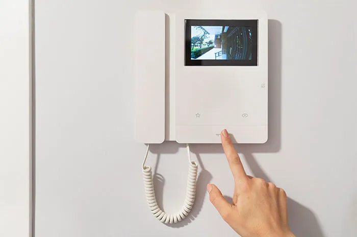 Person pressing button on an indoor video intercom system capturing bizarre and paranormal experiences at home.