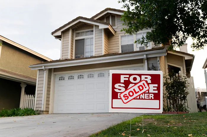 Suburban house with a sold sign on the lawn representing bizarre and paranormal experiences people can’t make sense of.