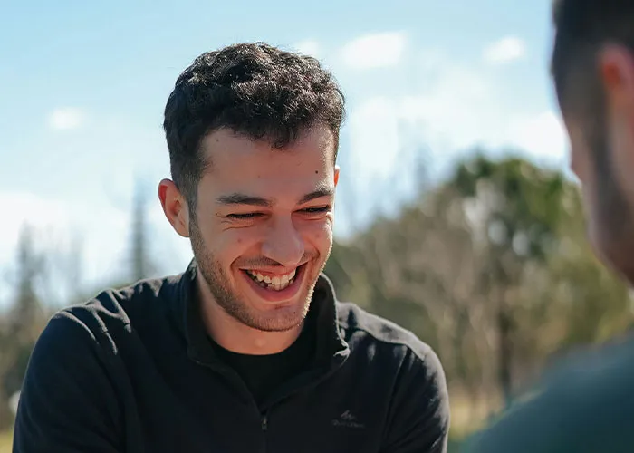 Young man smiling outdoors, illustrating weird body quirks that highlight the fascinating human body behavior.