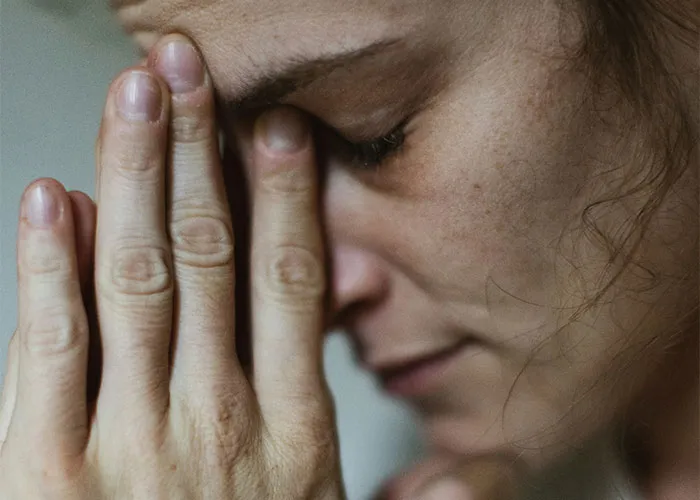 Close-up of a person with eyes closed and hands pressed together, illustrating unusual body quirks of the human body.