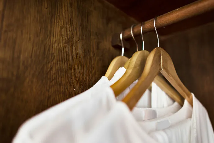 Wooden hangers with white shirts hanging inside a wooden closet, symbolizing the people who work and explore beneath our feet.