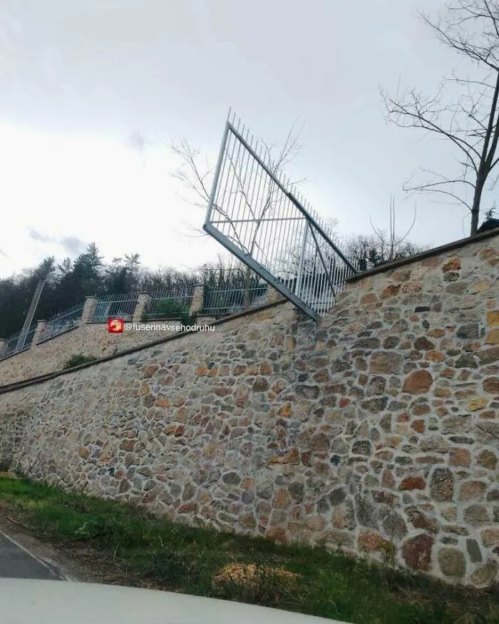 Reja suspendida sin soporte adecuado en muro de piedra, mostrando un divertido fallo de construcción llamativo y absurdo.