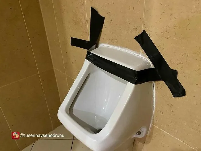 Orinal con cinta negra mal colocado, un divertido fallo de construcción que provoca risa y sorpresa.