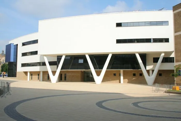 Modern building exterior with large white pillars, representing urban exploration and stories from beneath our feet.