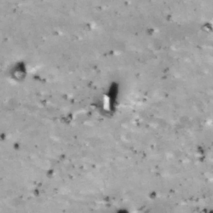 Blurry black and white photo showing a strange object casting a shadow on a textured surface in unexplained histories collection.