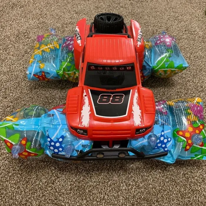 Red toy car modified with inflatable pool floaties, showcasing kids' inventive creations and surprising parents' reactions.