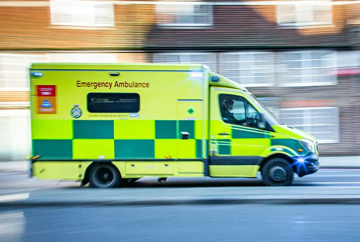 Emergency ambulance driving fast on city street, illustrating healthcare workers responding to critical life situations.