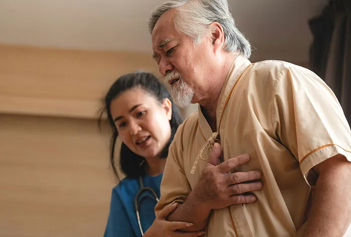 Healthcare worker assisting elderly man clutching chest, illustrating real-life emergency moments shared by healthcare workers.