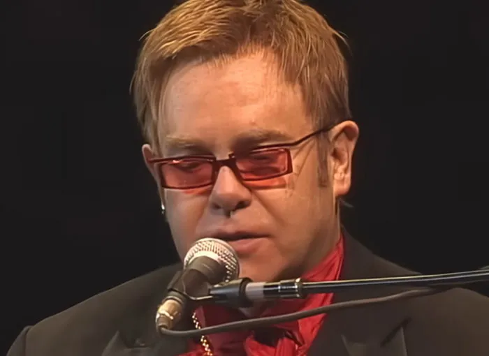 Musician performing at a piano with red-tinted glasses, featured in stories about people who knew celebrities before fame.