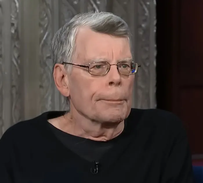 Elderly man with glasses wearing a black shirt, sharing stories about people who knew celebrities before fame.