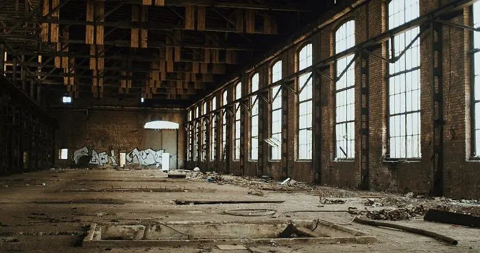Abandoned underground industrial space with debris and large windows, evoking stories from people who explore beneath our feet.