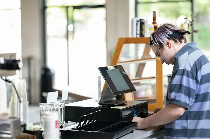 Young worker making mistakes at cash register, illustrating times people got fired due to dumb actions at work.