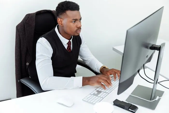 Young professional man working intently on a computer, representing someone who was the villain in another’s story.