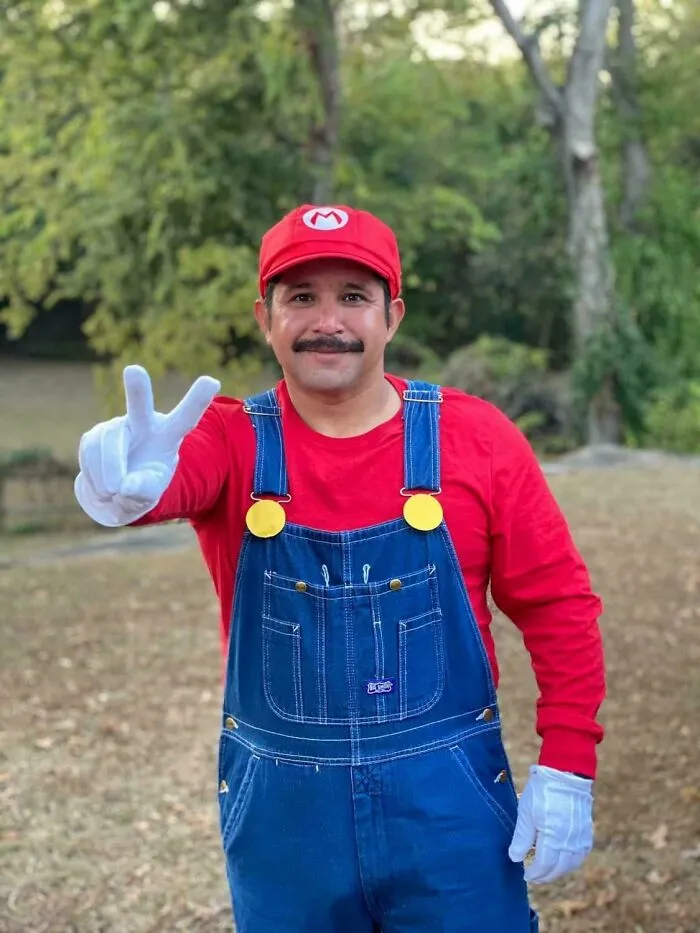 Man wearing a creative Halloween costume inspired by a popular video game character, outdoors in a park setting.