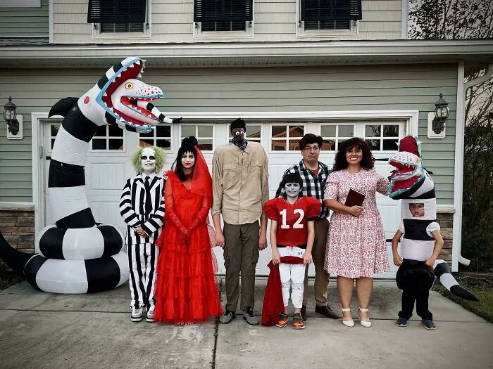 A family dressed in creative Halloween costumes standing in front of a house, showcasing genius Halloween costumes.