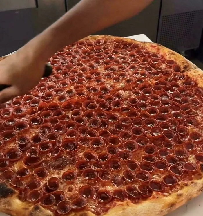 Large pepperoni pizza with tightly clustered pepperoni slices creating a trypophobia nightmare fuel effect.