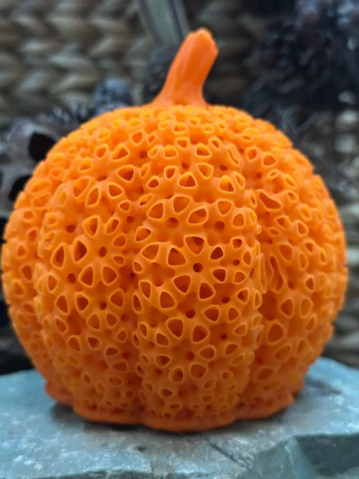 Close-up of an orange pumpkin-like object with numerous small holes, triggering trypophobia discomfort.