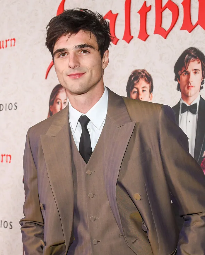 Jacob Elordi in a brown suit and black tie posing confidently at an event, representing handsome man in the world 2025.