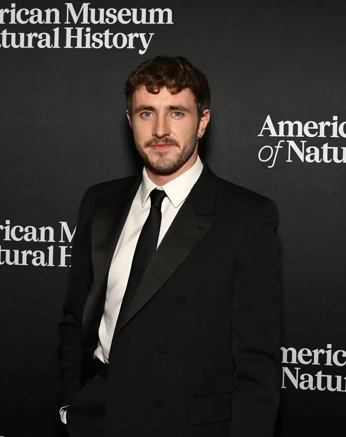 Paul Mescal in black suit and tie posing at American Museum event, representing most handsome man in the world 2025.