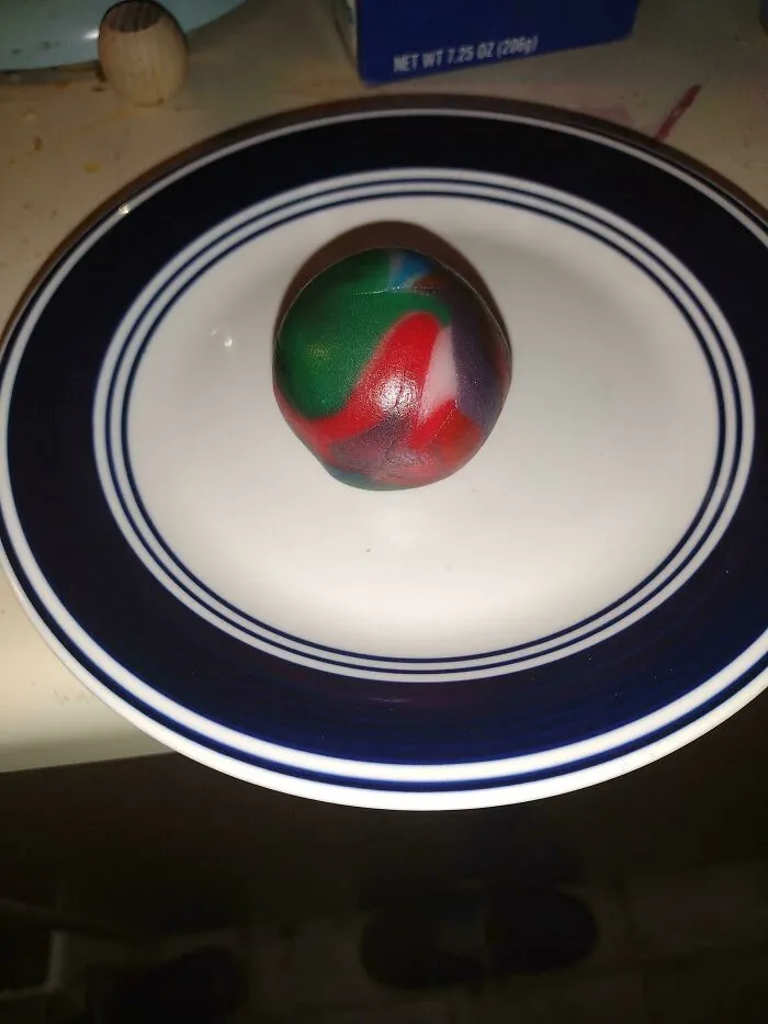 Multicolored round object on a white plate with blue stripes, one of many unholy food pics that look anything but appetizing.