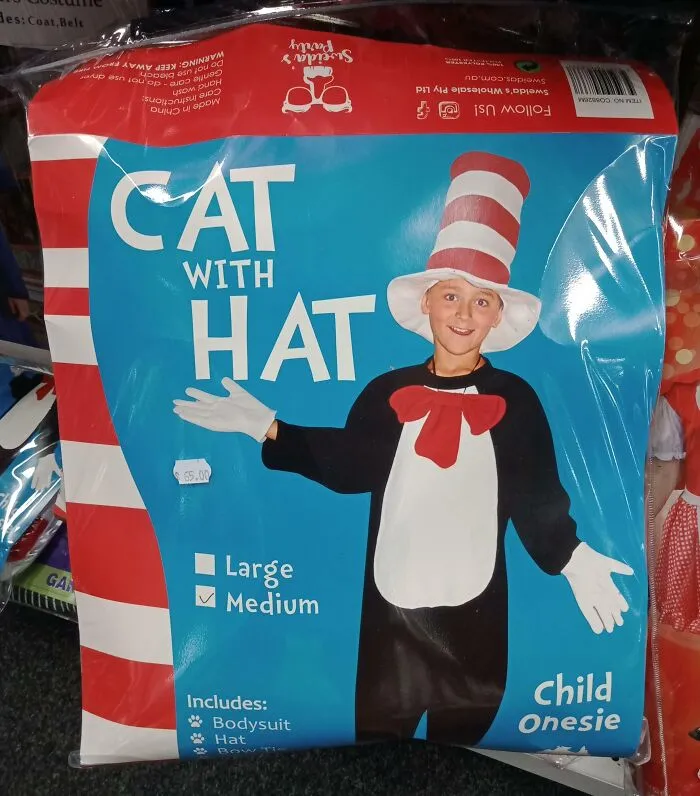 Child wearing an off-brand Cat with Hat Halloween costume with bodysuit, hat, and bow tie in a store packaging.