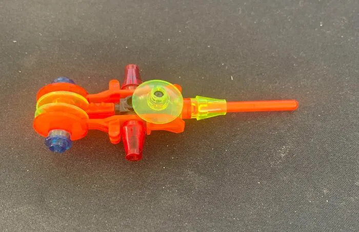 Colorful kid’s invention made from translucent red, yellow, and blue plastic parts on a dark surface, showcasing creativity.