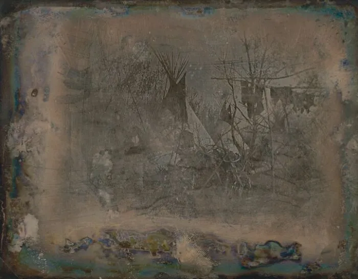 Early faded photo showing Native American teepees and trees, a rare image from the time when photography was new.