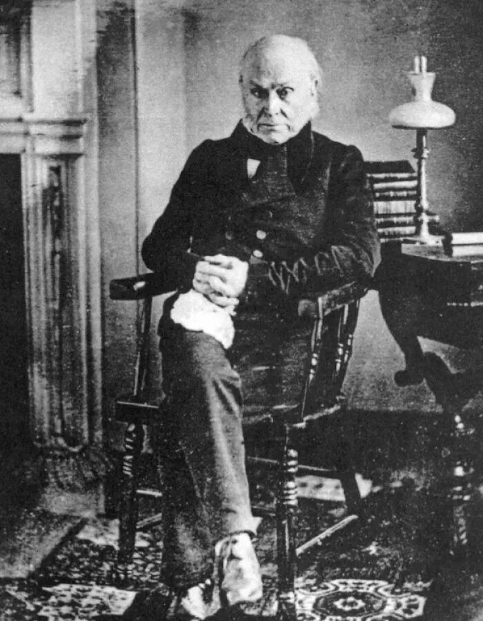 Early black and white photo of a man seated in a chair, one of the rare photos that survived from early photography.