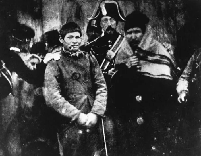 Early black and white photo showing a group of men in historical clothing from the time photography was new.