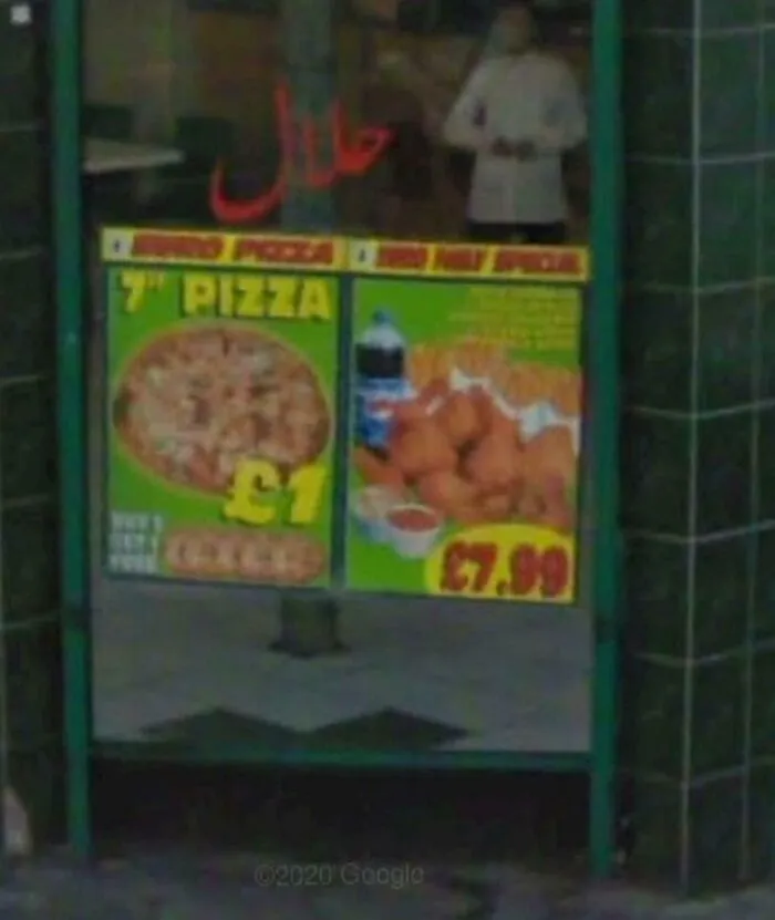 Street view showing pizza and food prices on a window, an unexpected capture from Google Earth and Maps.