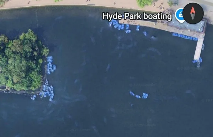 Aerial view of Hyde Park boating area showing clusters of blue paddle boats docked near the shore on Google Maps.